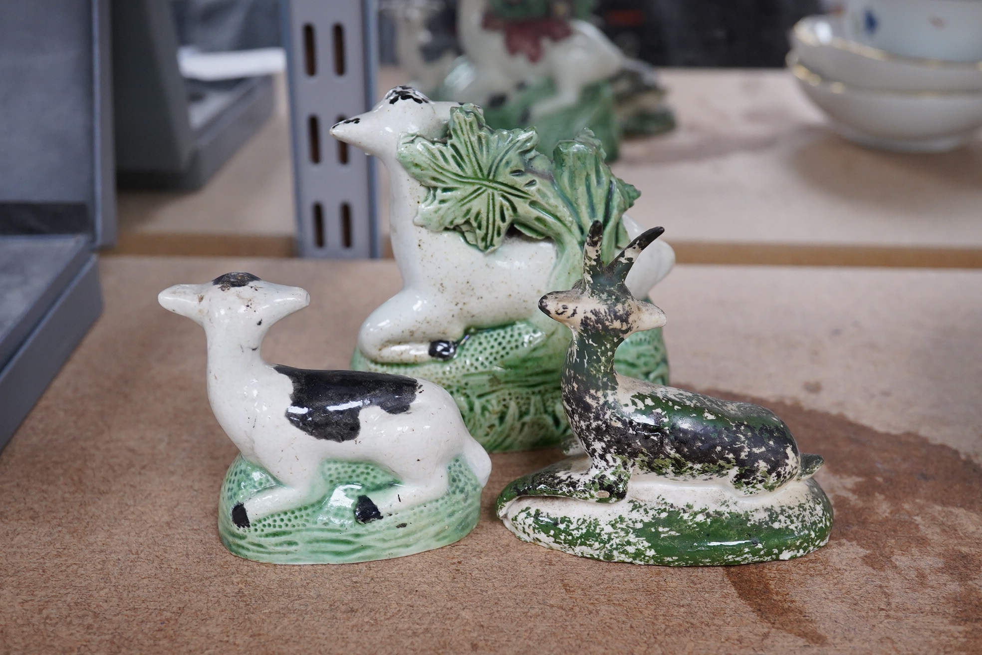 Two late 18th century Staffordshire coloured creamware figures of recumbent cows and a spongeware deer, largest 10cm wide (3). Condition - restored